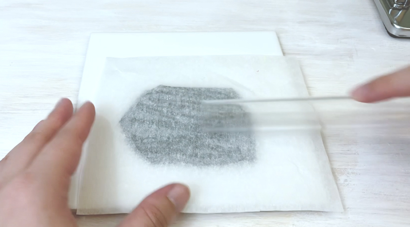 tracing paper on clay being rubbed with an acrylic roller